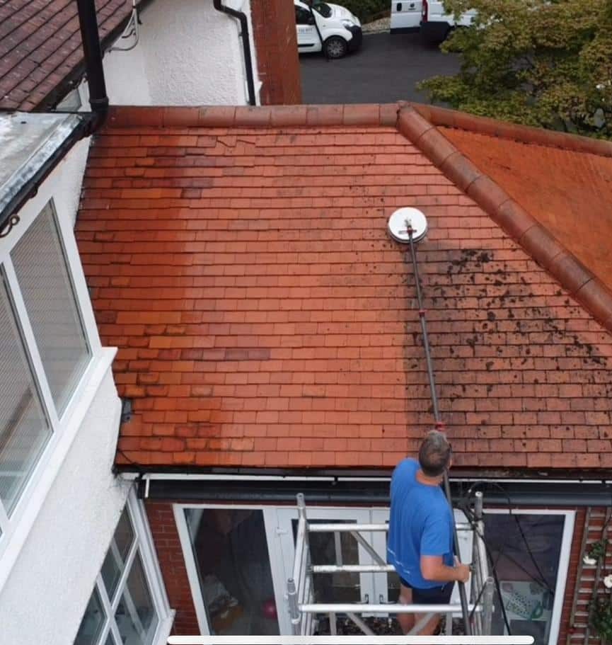 a man on a ladder on a roof impact exterior cleaning
